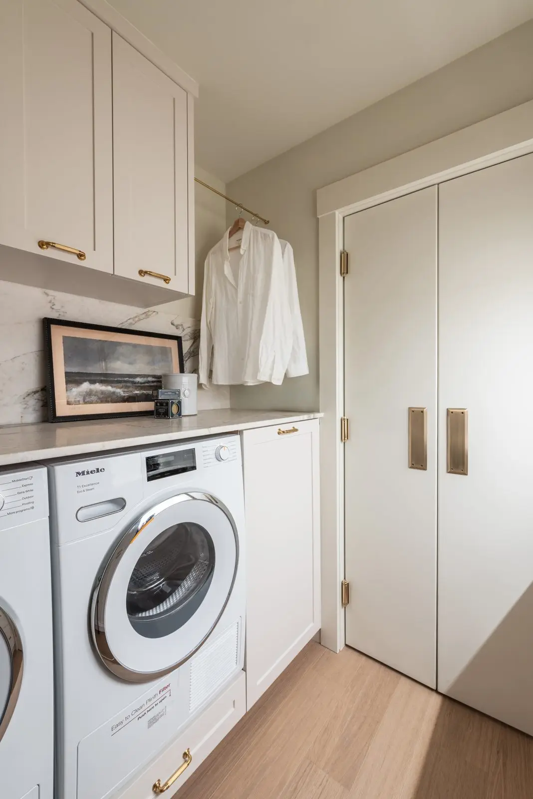 Modern Drift custom white laundry room cabinetry with painted shaker doors and full-height storage by Hempston Home