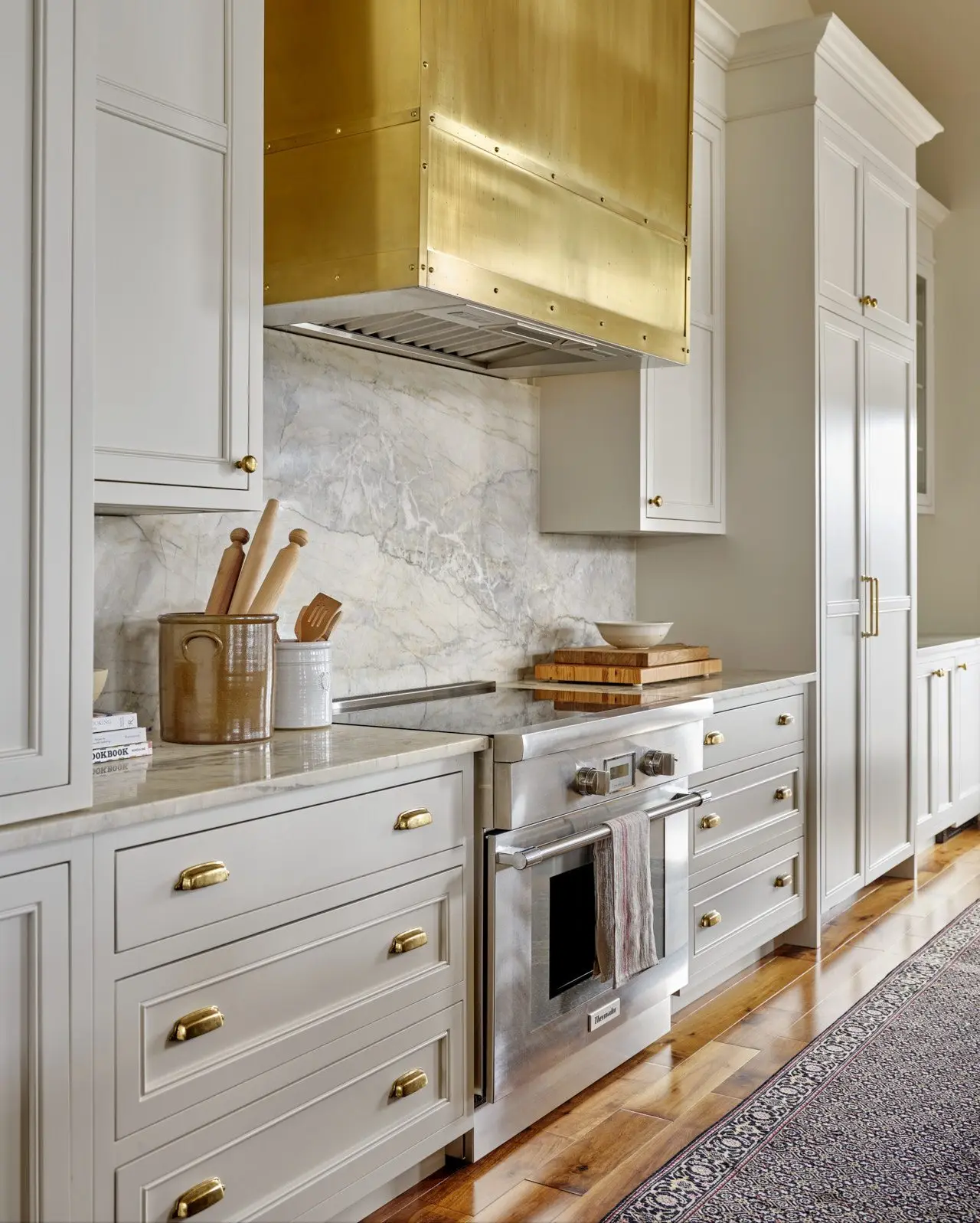 Hempston Home custom white painted shaker kitchen cabinetry with brass hood in Glen Haven, Nova Scotia
