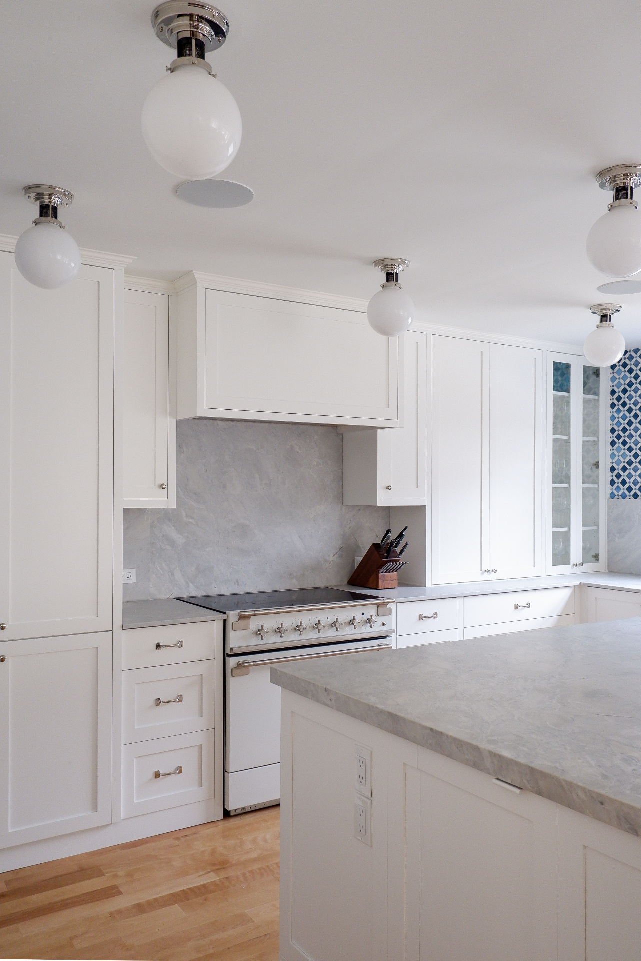 Custom white painted kitchen cabinetry with glass-front upper cabinets